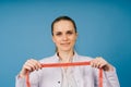 Young beautiful doctor woman in lab coat, studio shot, blue background Royalty Free Stock Photo