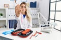 Young beautiful doctor woman with reflex hammer and medical instruments doing stop sing with palm of the hand Royalty Free Stock Photo