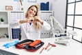 Young beautiful doctor woman with reflex hammer and medical instruments smiling in love doing heart symbol shape with hands Royalty Free Stock Photo