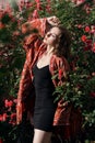 Young beautiful dreamy woman with closed eyes posing in the rose garden. Outdoor fashion portrait of romantic girl with hard light Royalty Free Stock Photo