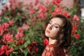 Young beautiful dreamy woman with closed eyes posing in the rose garden. Outdoor fashion portrait of romantic girl with hard light Royalty Free Stock Photo