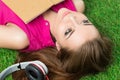 Young beautiful dreamy woman laying on grass in the park