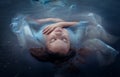 Young beautiful drowned woman in blue dress lying in the water