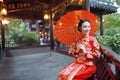 Young, beautiful and elegant Chinese woman wearing a typical Chinese bride`s silk red dress, adorned with golden phoenix and drago Royalty Free Stock Photo