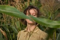 Young beautiful elegant girl with trendy gold makeup in green corn field holding the stalks with her hands Royalty Free Stock Photo