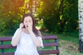 Young beautiful European girl brunette speaks on the phone in a city park and covers her face with her hands. surprised woman. une Royalty Free Stock Photo