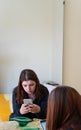 Young beautiful european girl sitting on bed thoughtfully using cellphone spending time alone in bedroom. back view of red head Royalty Free Stock Photo