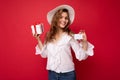 Young beautiful european stylish brunette woman wearing white blouse and fashionable hat isolated over red background Royalty Free Stock Photo