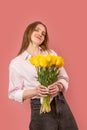 Young beautiful European woman spring bouquet of yellow flowers tulips in her hands. Isolated on pink background. women day. Royalty Free Stock Photo