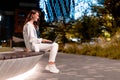 Young beautiful european woman using laptop computer in city park at night, sitting on bench, side view, copy space Royalty Free Stock Photo