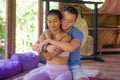 Young beautiful and exotic Asian Balinese woman receiving body healing Thai massage by attractive Caucasian masseur man at