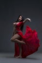 Young beautiful exotic eastern women performs belly dance in ethnic red dress on gray background Royalty Free Stock Photo