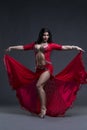 Young beautiful exotic eastern women performs belly dance in ethnic red dress on gray background Royalty Free Stock Photo