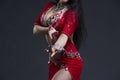 Young beautiful exotic eastern women performs belly dance in ethnic red dress on gray background Royalty Free Stock Photo