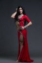 Young beautiful exotic eastern women performs belly dance in ethnic red dress on gray background Royalty Free Stock Photo