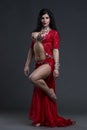 Young beautiful exotic eastern women performs belly dance in ethnic red dress on gray background Royalty Free Stock Photo