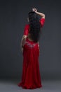 Young beautiful exotic eastern women performs belly dance in ethnic red dress on gray background Royalty Free Stock Photo