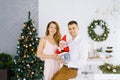 A young beautiful family with a five-month-old baby in a little Santa costume in the arms of their parents. Happy family celebrate Royalty Free Stock Photo