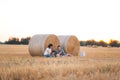 Young beautiful family have rest in field with hay stacks in summer at sunset Royalty Free Stock Photo