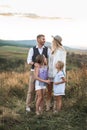 Young beautiful family posing and looking each other, while standing in a field, at summer sunset. Family relaxing in Royalty Free Stock Photo