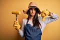 Young beautiful farmer woman wearing apron and hat holding fork with cob corn with angry face, negative sign showing dislike with Royalty Free Stock Photo