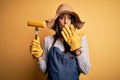 Young beautiful farmer woman wearing apron and hat holding fork with cob corn cover mouth with hand shocked with shame for Royalty Free Stock Photo