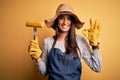 Young beautiful farmer woman wearing apron and hat holding fork with cob corn doing ok sign with fingers, excellent symbol Royalty Free Stock Photo