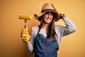 Young beautiful farmer woman wearing apron and hat holding fork with cob corn stressed with hand on head, shocked with shame and Royalty Free Stock Photo