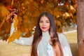 Young beautiful fashion brunette woman with red lips and long straight hair wearing a white sweater outdoor in autumn park. Royalty Free Stock Photo