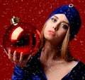 Young beautiful fashion woman in blue stylish winter dress and hat hold big christmas decoration ball Royalty Free Stock Photo