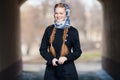 Young beautiful fashionable redhead woman with braids hairdo in blue white headcraft stylish denim black trench jacket posing outd Royalty Free Stock Photo