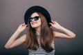 Young beautiful fashionable woman with trendy makeup in black hat and glasses on the grey background . Model looking at camera, w Royalty Free Stock Photo