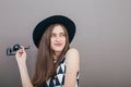 Young beautiful fashionable woman with trendy makeup in black hat and glasses on the grey background . Model looking at camera, w Royalty Free Stock Photo