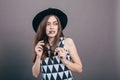 Young beautiful fashionable woman with trendy makeup in black hat and glasses on the grey background . Model looking at camera, w Royalty Free Stock Photo