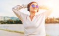 Young beautiful female in blue sunglasses listening to music using smartphone and wireless headphones cheerfully smiling. Walking Royalty Free Stock Photo