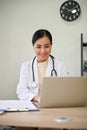 Young beautiful female doctor working with laptop in her clinic room Royalty Free Stock Photo