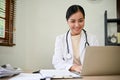 Young beautiful female doctor working with laptop in her clinic room Royalty Free Stock Photo
