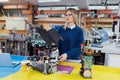 Young beautiful female engineer testing robot in workshop