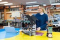 Young beautiful female engineer testing robot in workshop