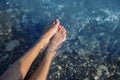 Young and beautiful female feet with red painted nails on a beach under waves. Royalty Free Stock Photo