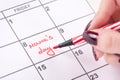 Woman hands with red felt pen writes words Mamas day in calendar