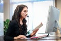 Young beautiful female with headphones working at call center service desk consultant, talking with the customer on hands-free Royalty Free Stock Photo