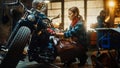 Young Beautiful Female Mechanic is Working on a Custom Bobber Motorcycle. Talented Girl Wearing a Royalty Free Stock Photo