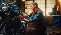 Young Beautiful Female Mechanic is Working on a Custom Bobber Motorcycle. Talented Girl Wearing a Royalty Free Stock Photo