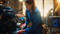 Young Beautiful Female Mechanic is Working on a Custom Bobber Motorcycle. Talented Girl Wearing a Royalty Free Stock Photo