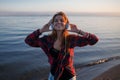 Young beautiful female music fan. Dancing and listening to music on headphones. Portrait on the sea background