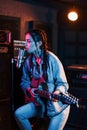 Young beautiful female performer with guitar singing and rehearsing in a recording studio Royalty Free Stock Photo