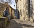 Young beautiful female sitting on rock wall looking the landscape in old medieval town of Rupit Barcelona Spain