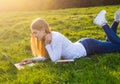 Young beautiful girl-student with a laptop lies on the grass in Royalty Free Stock Photo