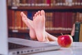 Young beautiful female student studies and reads books in the library. Selective focus on the feet Royalty Free Stock Photo